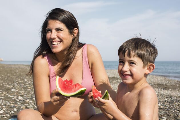 乐趣亲密的女人和男孩在吃西瓜海滩生活方式夏天