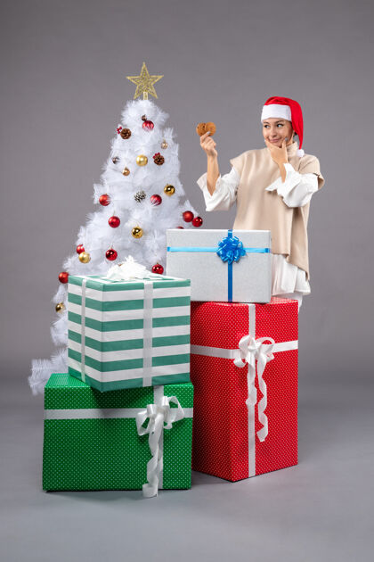 衣服在圣诞树旁拿着饼干和礼物的年轻女子时尚礼物持有