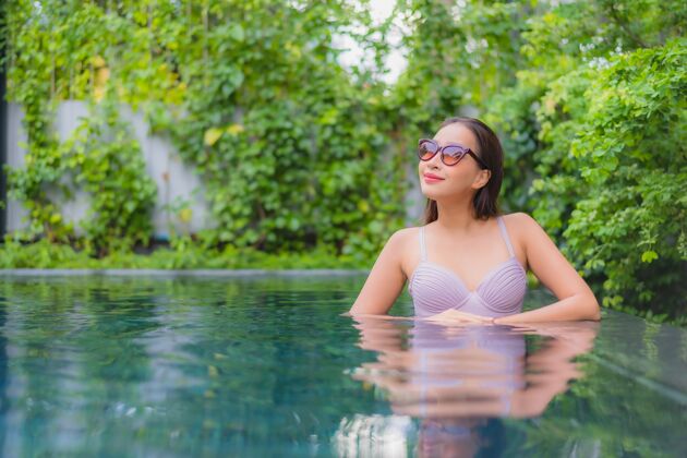 年轻肖像美丽的亚洲年轻女子放松微笑休闲在酒店度假村的室外游泳池周围度假村享受酒店