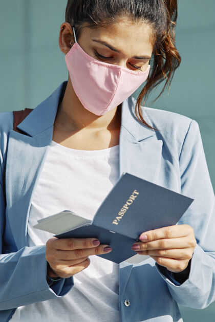 Ncov带着医用口罩在机场检查护照的女人垂直口罩交通