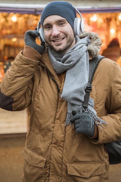 年轻一个戴着冬季耳罩的男人的画像镜头视图快乐