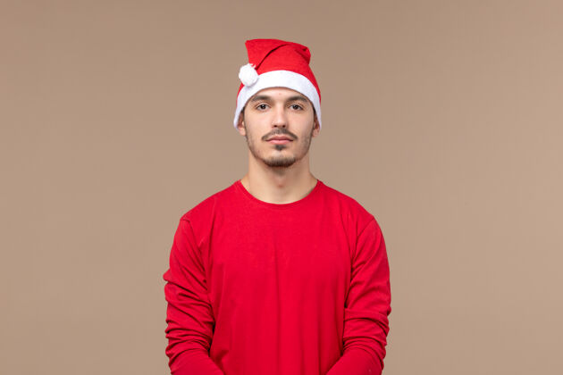 浴帽正面图：棕色背景上穿着圣诞斗篷的年轻男性圣诞情绪年轻微笑人