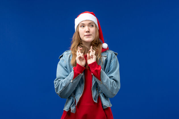 微笑前视图年轻女性交叉她的手指蓝色背景新年假期圣诞节蓝色年轻手指