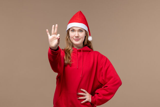 节日前视图年轻女性显示在棕色背景上的数字情感圣诞假期帽子漂亮人物