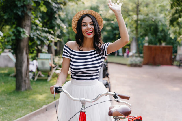 街道兴奋的棕褐色女士在夏天的周末表达快乐的情绪漂亮的年轻女子在户外骑自行车快乐女士自行车