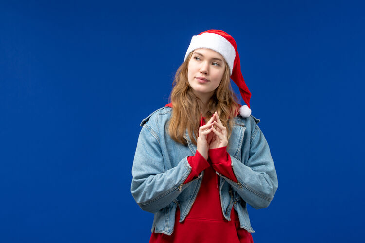 成人正面图蓝色背景上戴着红色圣诞帽的年轻女性圣诞节情感假期服装人物人物