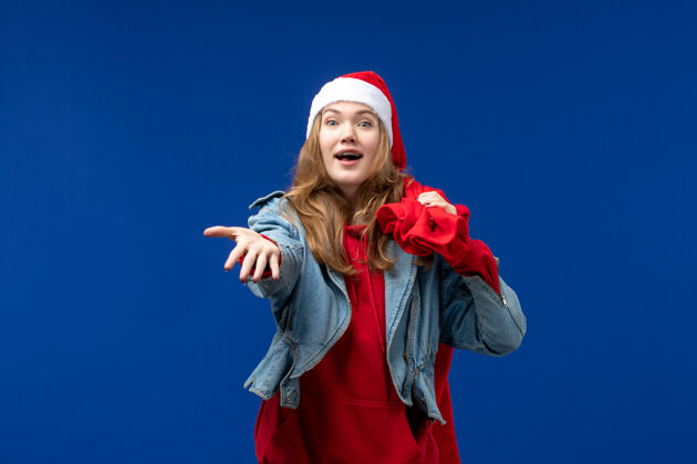 肖像正面图：年轻女性拎着装满礼物的袋子在蓝色地板上 感慨圣诞节地板颜色年轻女性
