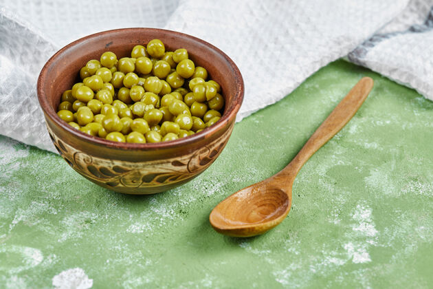 绿色一碗煮青豌豆 一个木勺和一块桌布食物烹饪木制