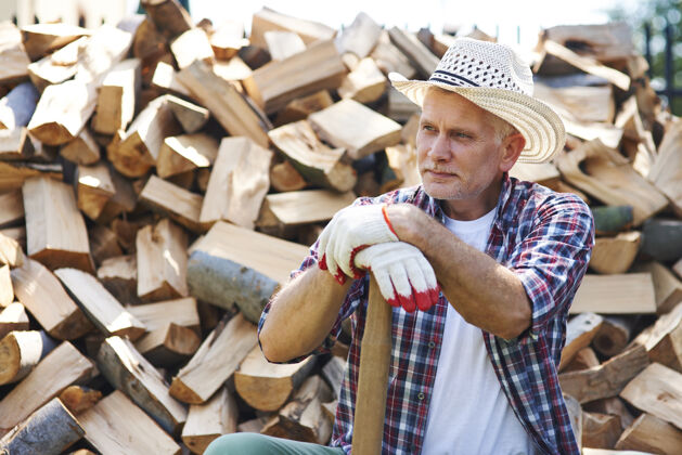 放松成熟的伐木工人在劈柴后休息户外沉思树干