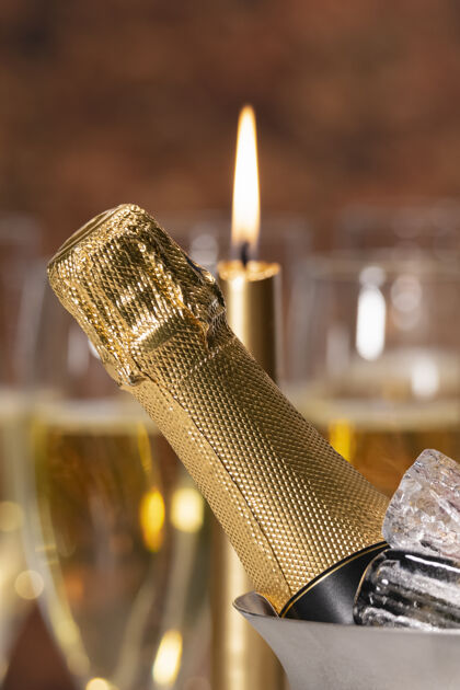 年一个香槟酒瓶 里面有冰块和一根在后面点燃的蜡烛庆祝的概念优雅房子庆祝活动