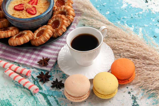 早餐前视图美味的糖饼干与麦卡龙咖啡杯和草莓甜点蓝色表面饼干饼干甜点糖蛋糕杯子生的膳食