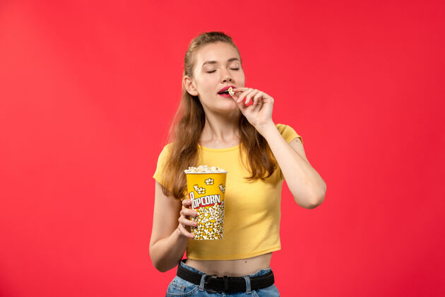 剧院正面图年轻女子在电影院拿着爆米花在红墙电影院吃电影的女孩漂亮成人电影