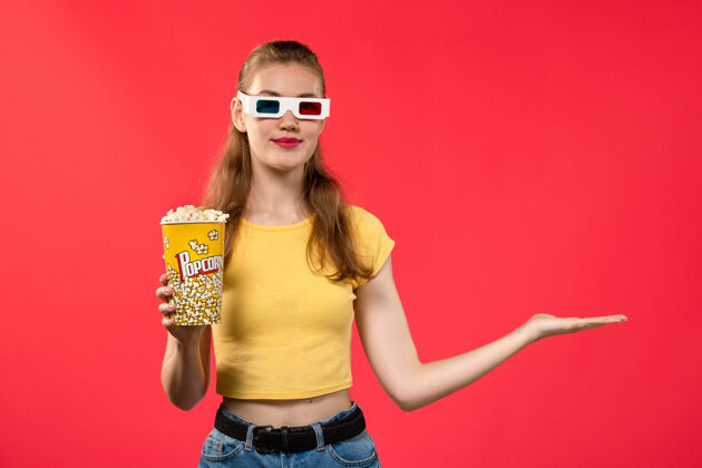 电影正面图年轻的女性在电影院拿着爆米花在红墙电影院电影院小吃女性趣味电影女性剧院小吃