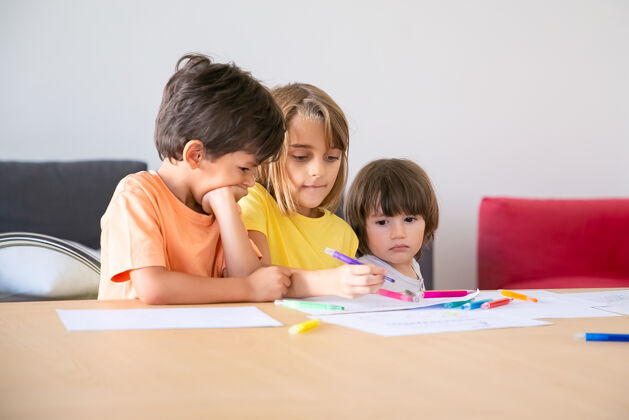 沙发沉思的孩子们在客厅里用记号笔画画三个可爱的白人孩子坐在一起 享受生活 一起画画 一起玩耍童年 创造力和周末的概念钢笔儿童可爱