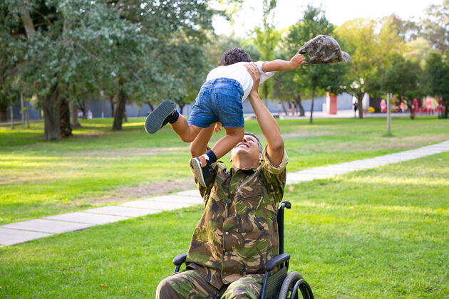 成人快乐残疾军人父亲坐轮椅回家 抱着儿子 抱着男孩 抱着他退伍军人还是家庭团圆的概念孩子残疾受伤