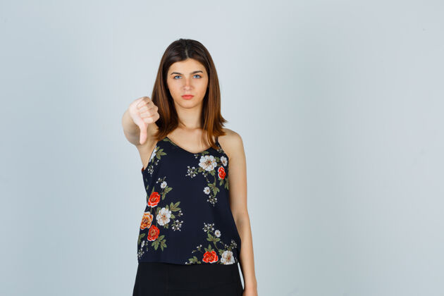 人美丽的年轻女性的肖像展示拇指在衬衫痛苦衬衫问题