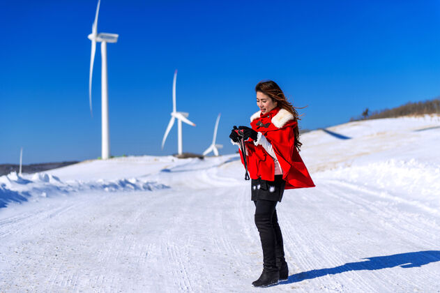 推年轻的女人是一个幸福的冬天用相机在天空和冬天的道路上用雪和红衣服快照摄影师拍摄