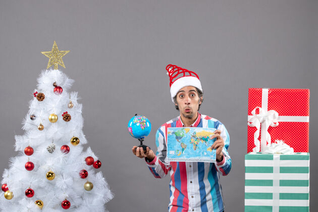 举行前视图好奇的男子与螺旋弹簧圣诞帽举行世界地图和地球仪春天圣诞节地球仪