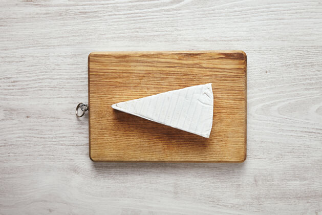 圆形白色新鲜三角形的美味布里干酪放在砧板上 中间的白色陈年木桌上可供用餐 早餐可供享用展示概念开胃菜膳食奶油