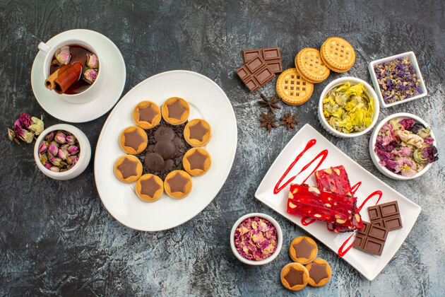 视图一盘饼干和巧克力 一杯花草茶和灰色的干花草药饼干和巧克力营养品