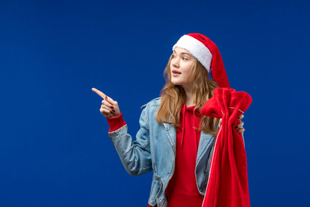 礼物正面图蓝色书桌上的年轻女性拿着带礼物的包圣诞节假期感慨表演者女性年轻女性