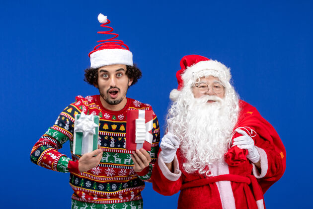 男性正面图：圣诞老人和手持礼物的年轻男性圣诞人们年轻