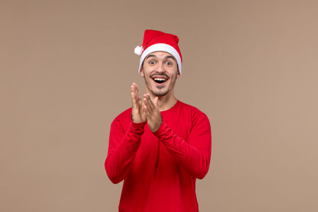 漂亮正面图：年轻男性 在一个棕色背景的圣诞假期里 表情激动节日微笑男性