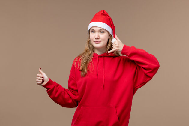 快乐正面图：年轻女性在棕色背景下微笑着摆出圣诞情感假期的姿势节日人情感