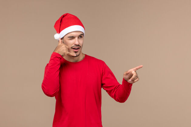 男人正面图棕色背景上表情眨眼的年轻男性圣诞假期感慨情感表情棕色