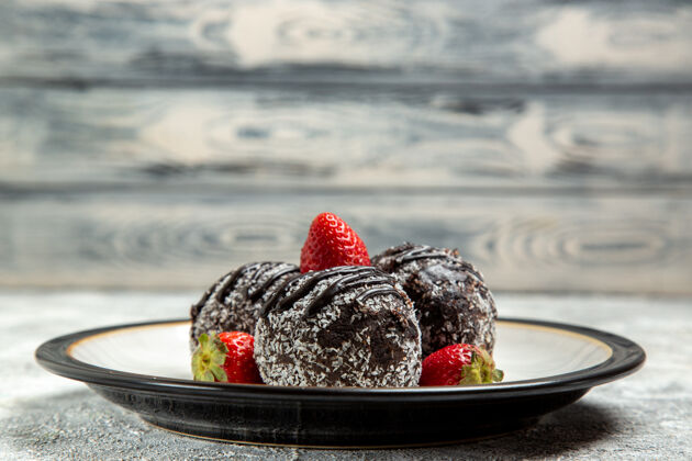 覆盆子正面是美味的巧克力蛋糕 白色表面有新鲜的红色草莓巧克力糖饼干甜蛋糕烤饼干生的水果浆果