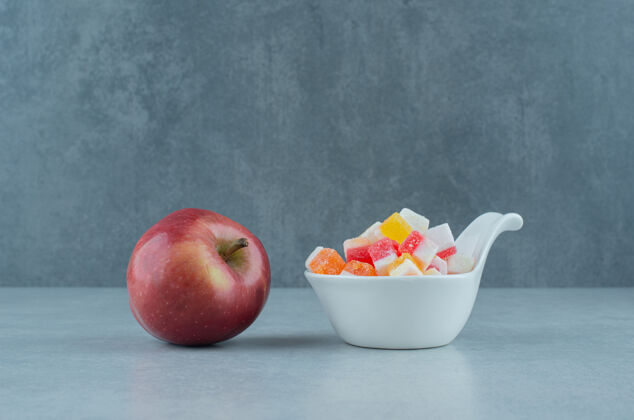 水果一碗糖果和一个新鲜的苹果放在大理石上有机糖果苹果