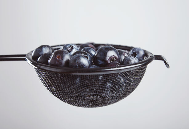 成熟的把一堆新鲜的蓝莓放在黑色的容器里 洗净后即可食用非常适合做清淡的早餐 多汁的健康饮食食品覆盆子甜点小吃