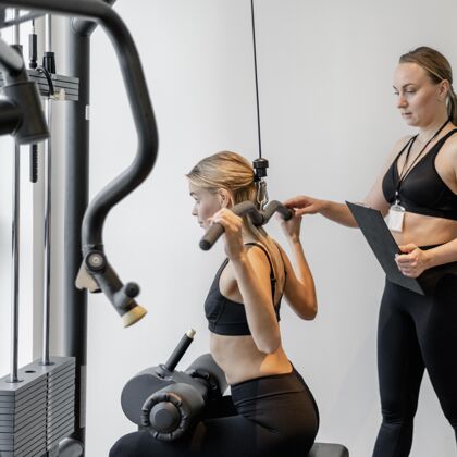 客户年轻女子在健身房锻炼侧视图教练运动训练