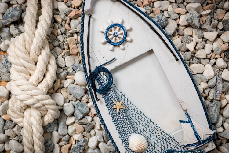 鹅卵石船形的木制观景架躺在鹅卵石上绳子海洋结