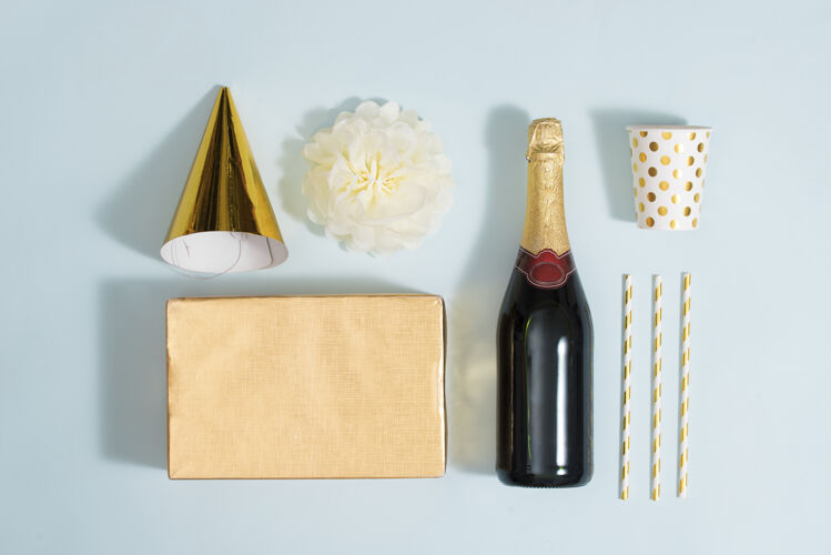 玻璃平放圣诞或派对背景 带礼品盒 香槟瓶 蝴蝶结 装饰品和金色包装纸平放 俯视图香槟冬天季节
