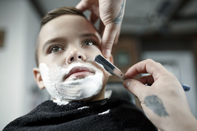 男人儿童理发师在黑暗中剪小男孩孩子专业理发师
