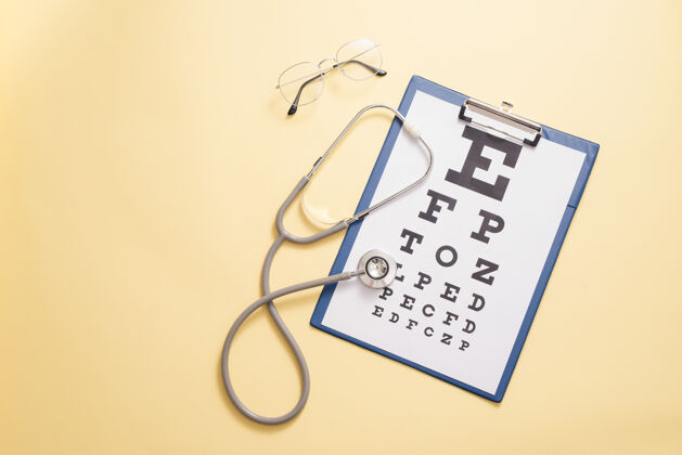 光学视力测试和医用听诊器的表格为黄色背景眼科诊断的概念 眼科疾病的检测特写检查眼镜