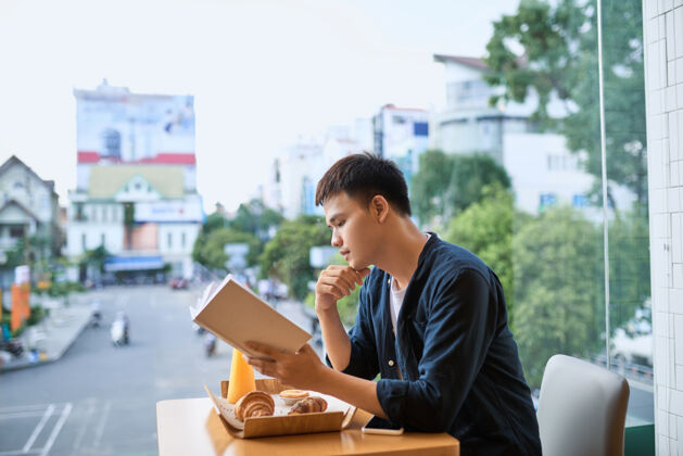 亚洲人在咖啡店看书的人早餐聪明举行