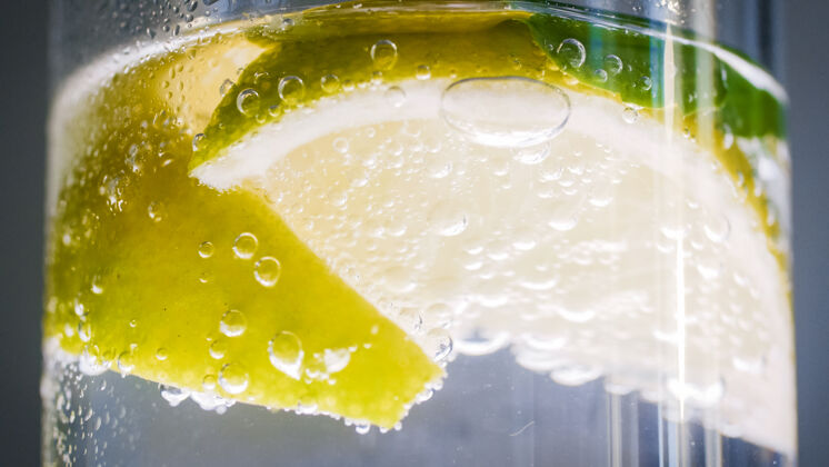 工具气泡和柠檬片漂浮在冷柠檬水中的特写照片汽水柠檬水