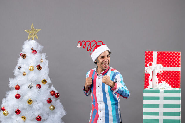 站立正面图自信的快乐男人站在白色圣诞树旁微笑男性快乐