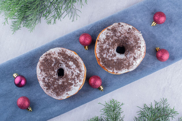 桌布美味的甜甜圈和圣诞装饰品放在白色背景的折叠桌布上装饰圣诞树开胃