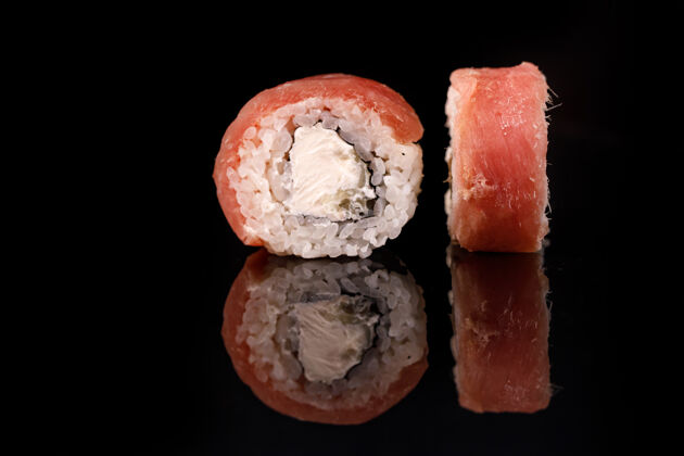 海鲜金枪鱼寿司卷在一个黑色的表面反射大豆观点酱汁