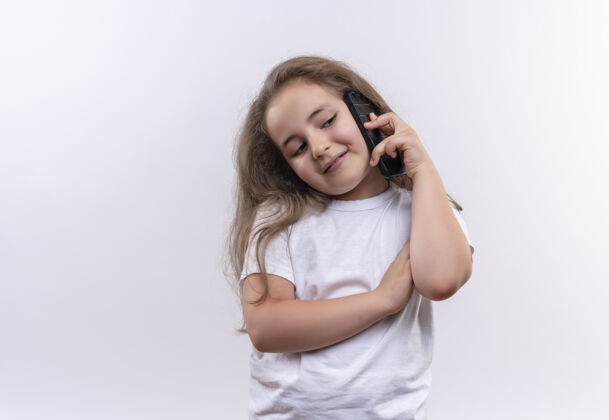T恤微笑的小女孩穿着白色t恤在孤立的白色背景下讲电话电话微笑说话