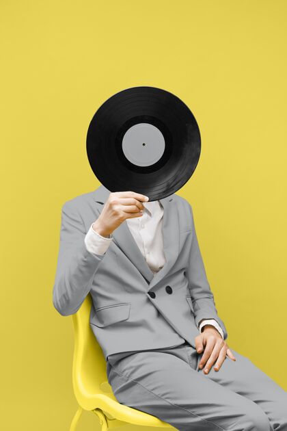 黄色一个男人用一张黑胶唱片遮住他的脸 同时穿着一身灰色的衣服乙烯基年份人物