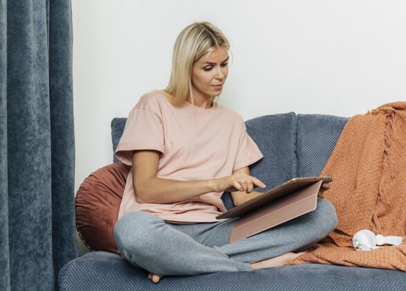 隔离在沙发上使用平板电脑的妇女在家的前视图预防隔离流行病
