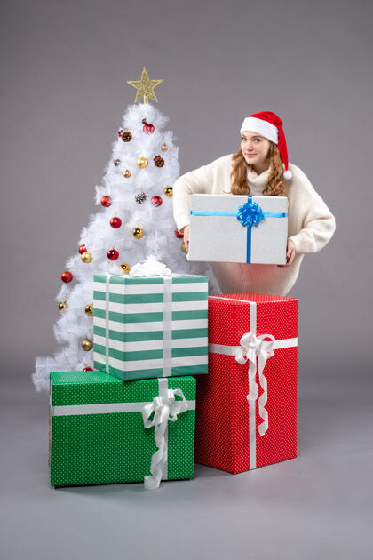 包在灰色地板上的圣诞礼物周围的年轻女性礼物圣诞老人圣诞树