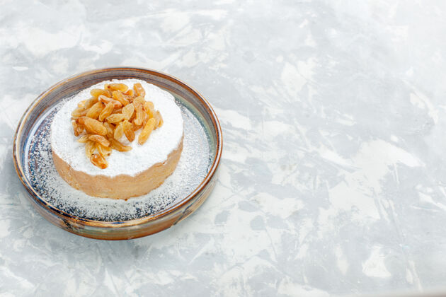 早餐正面图糖粉葡萄干葡萄干放在小蛋糕上面 盘子里放在白色桌子上葡萄干水果糖甜蛋糕饼干派干的盘子派