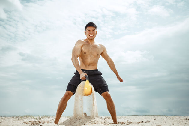 锻炼年轻健康的男子运动员在海滩上做深蹲健身白种人强壮