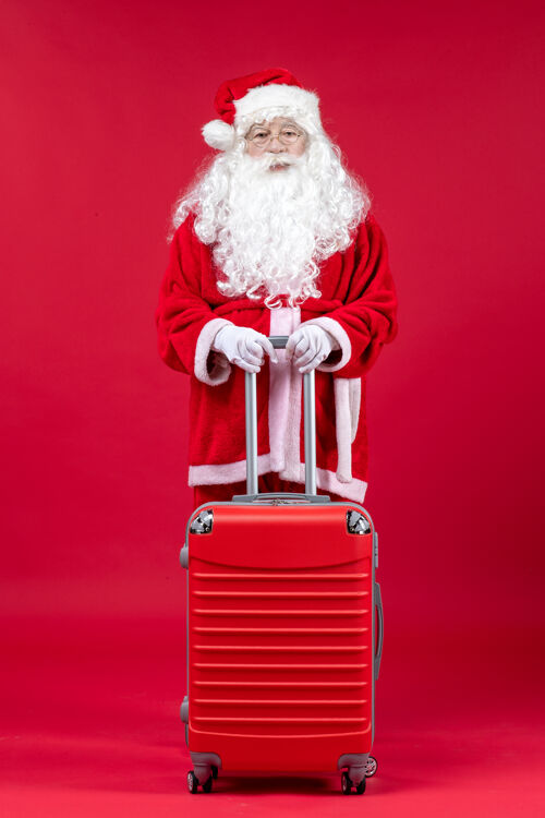 人圣诞老人的正面图 红色的墙上挂着他的红色袋子人手推车人
