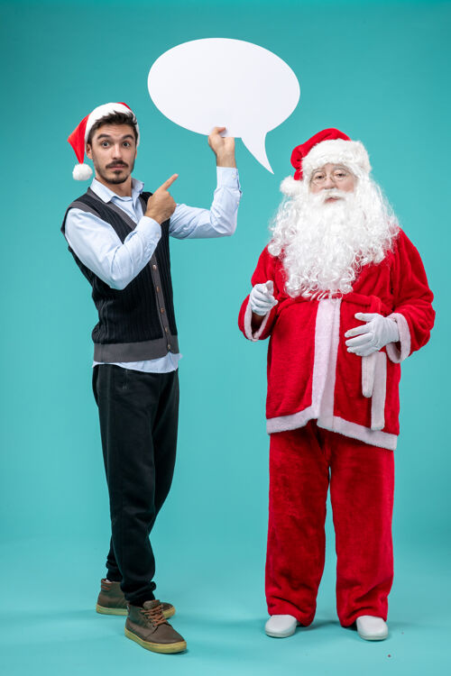 白色前视图圣诞老人和年轻的男性谁持有蓝色背景上的白色标志前面成人男性